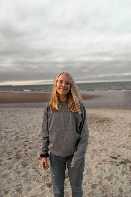 a woman in grey shirt standing on sandy beach