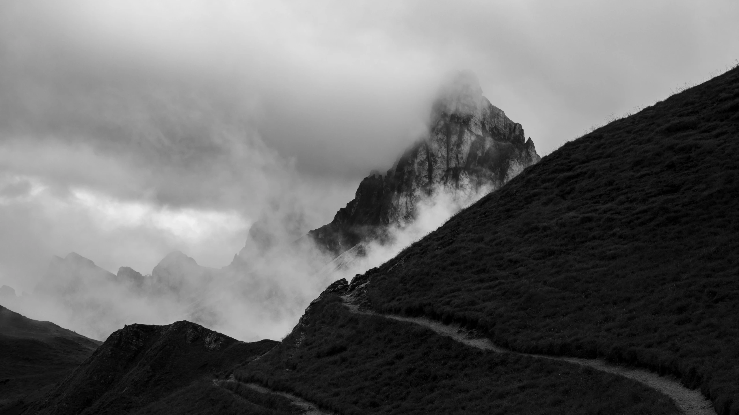 a black and white image of a mountain range with clouds