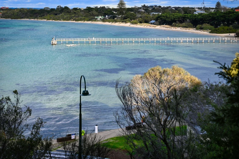 the beautiful blue ocean with a bridge that is next to it