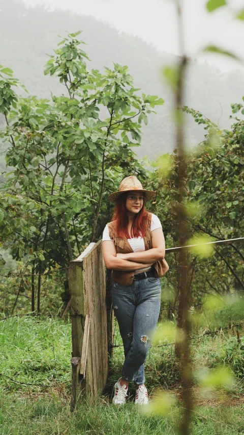 a young woman leaning against a fence in the countryside