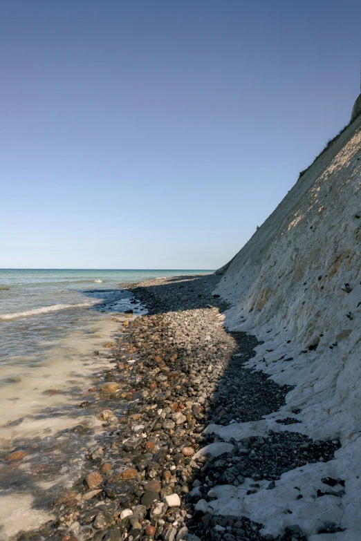 a sandy beach with a stop sign on the cliff