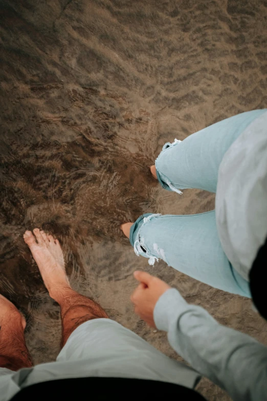 two people are sitting by the water looking down