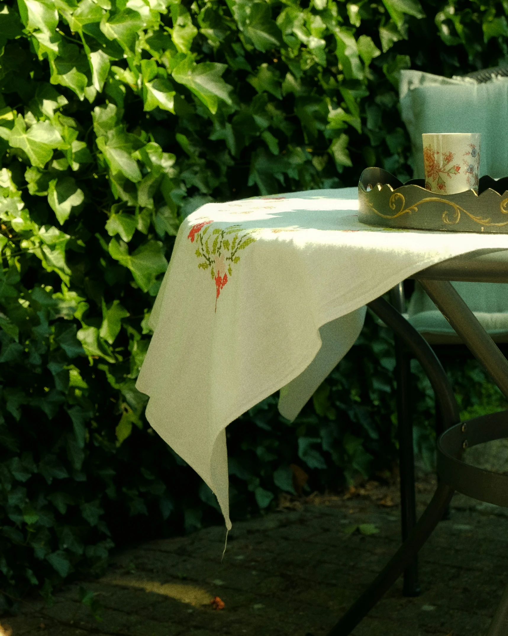 a chair is next to a table with a white and green tablecloth on it