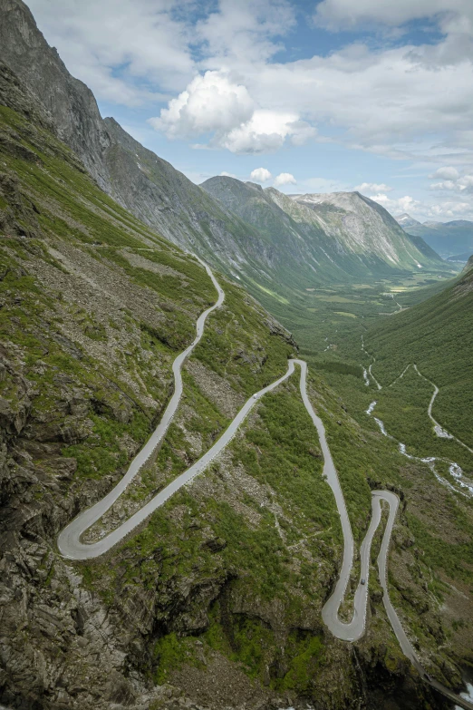 a winding road curves up a grassy mountainside