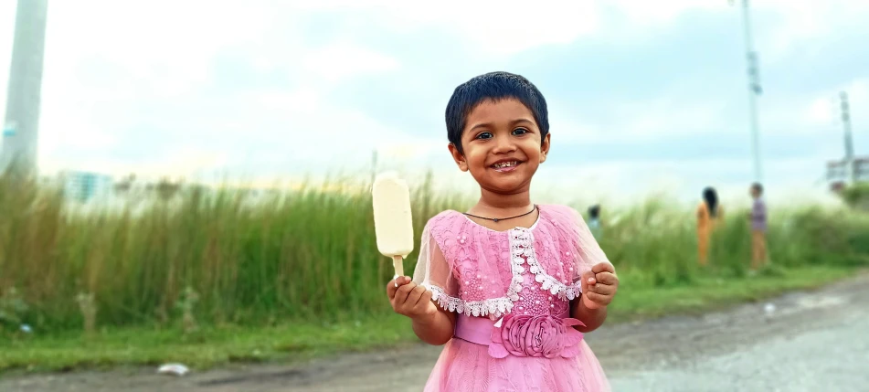 a young child standing by a road holding a spatula