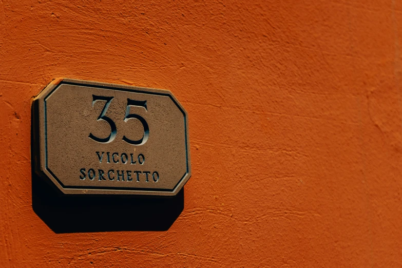 a number 35 sign on a orange stucco wall