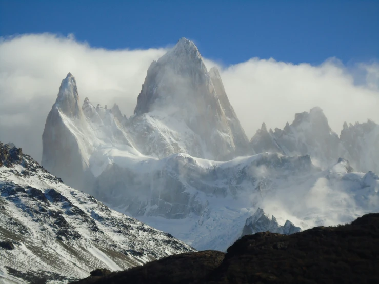 a mountain with a snow capped peak and cloud around it