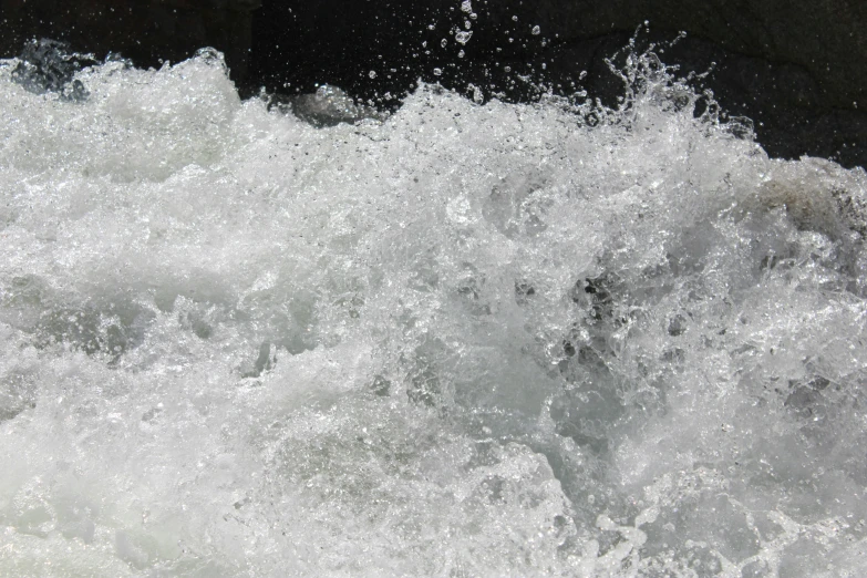 a wave crashes into the water on top of a rock