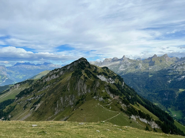 the peak of a mountain with green grassy area in front