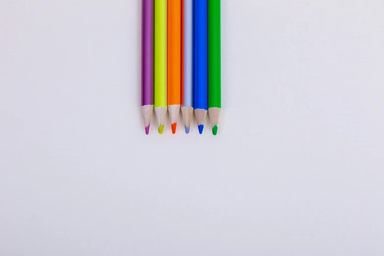 four colorful pencils are laying side - by - side in front of a white background