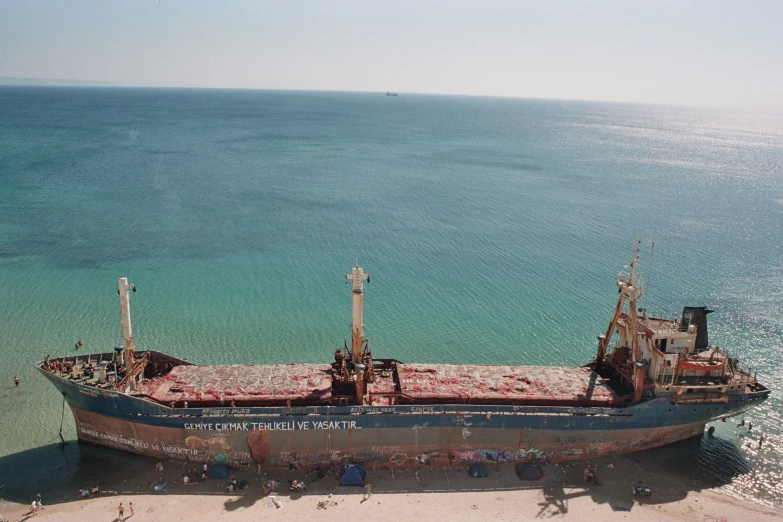 a large ship on top of sand next to water
