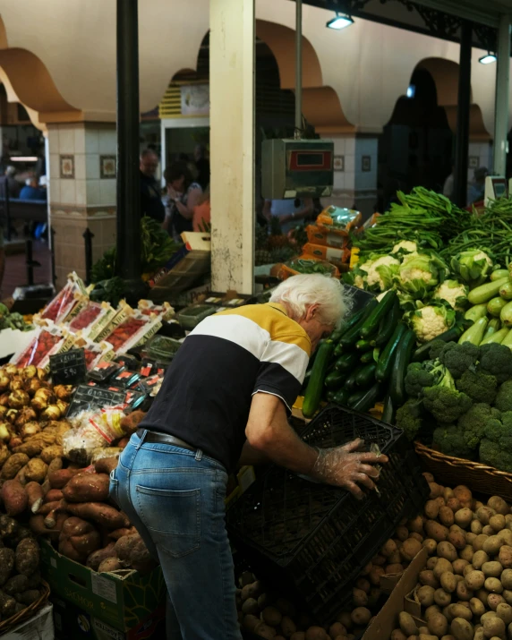 a man is picking up a lot of vegtables