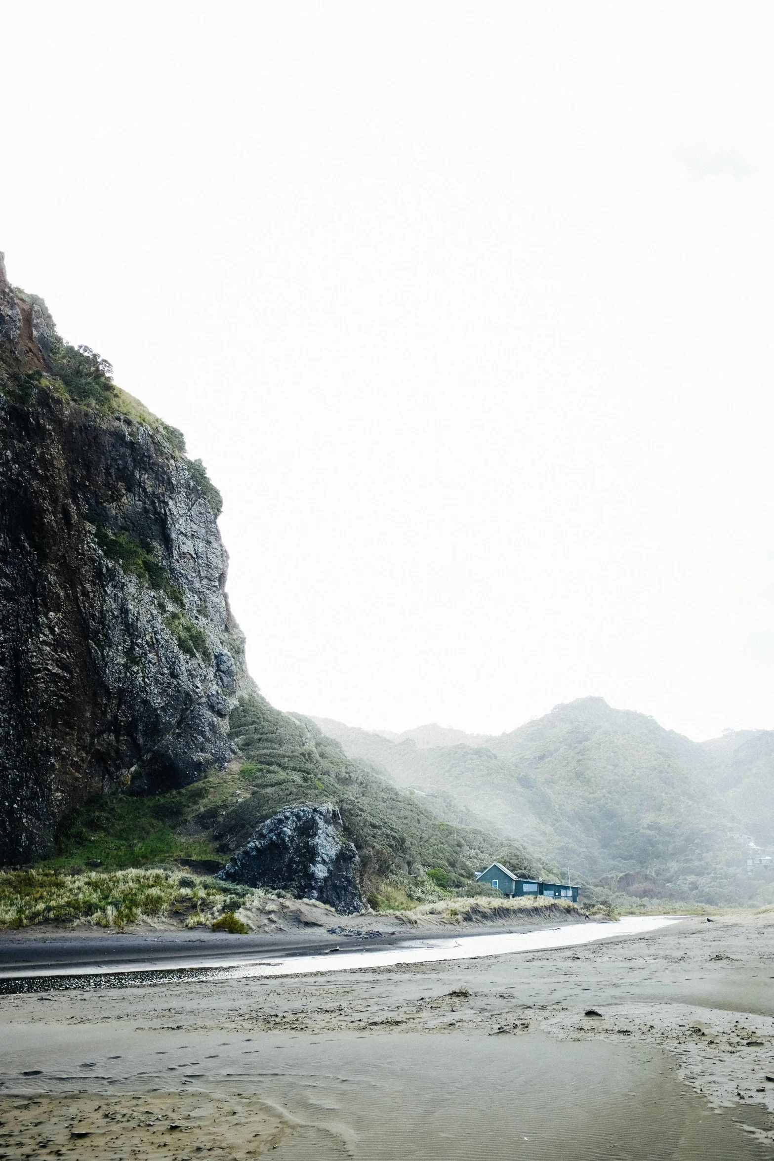 a beach with mountains and a truck in the distance