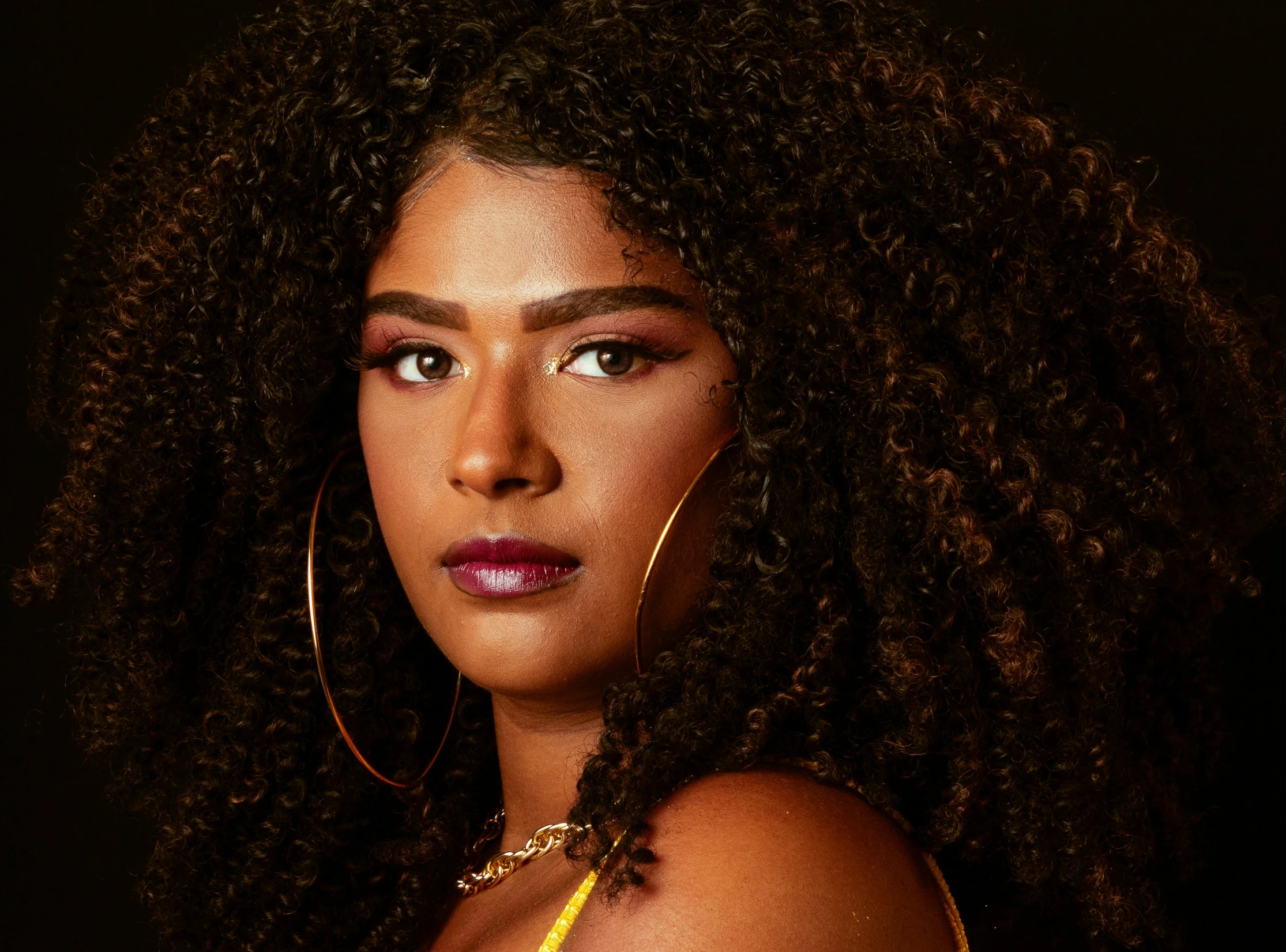 a woman with large earrings is staring at the camera