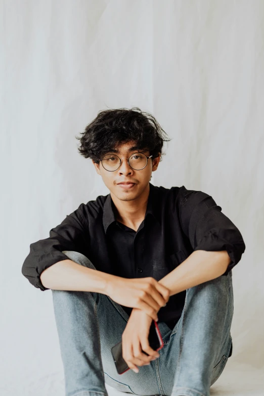 a young man sits on the ground while posing