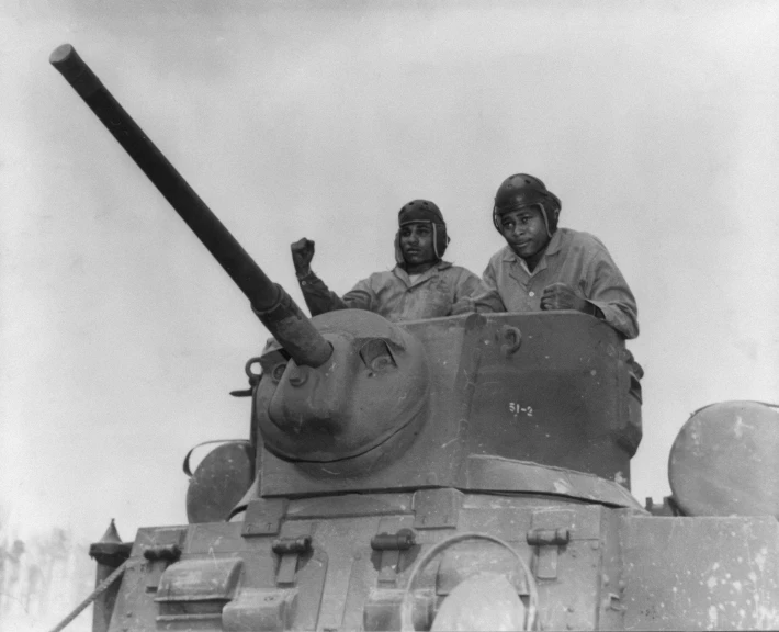 two men sitting on top of an army tank