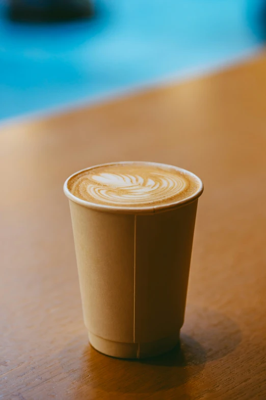 the cup is sitting on the wooden table by itself