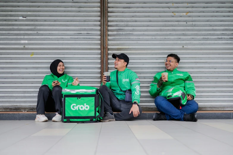 three people sit outside together in green shirts