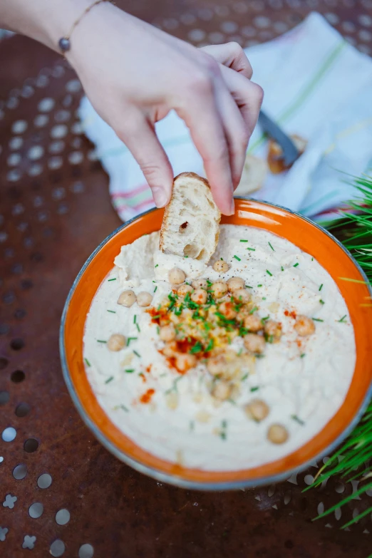 a hand about to dip a white dish filled with dip