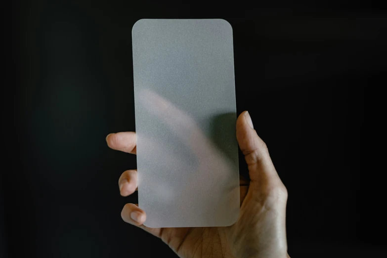 a person holding a small rectangular grey piece of paper