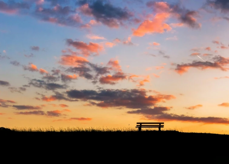 bench at sunset on top of hill with red clouds