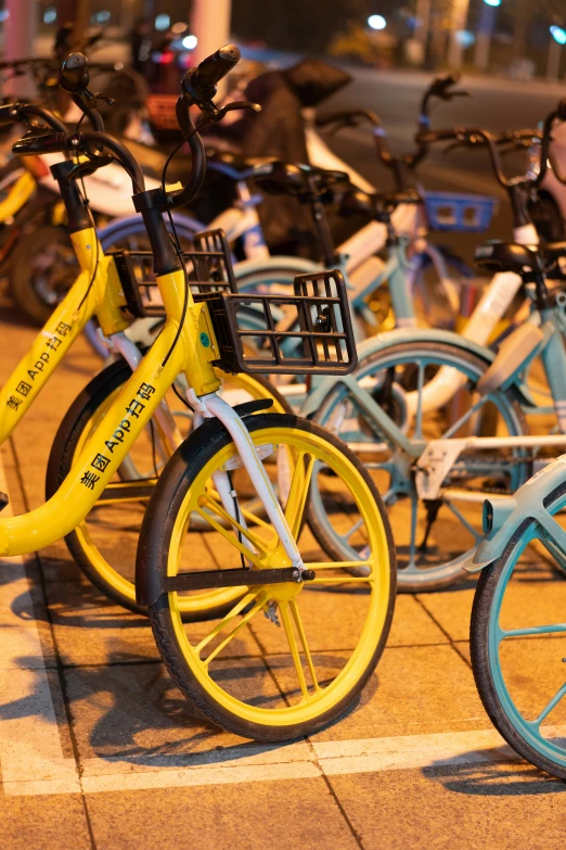 several colorful bikes parked side by side on the sidewalk