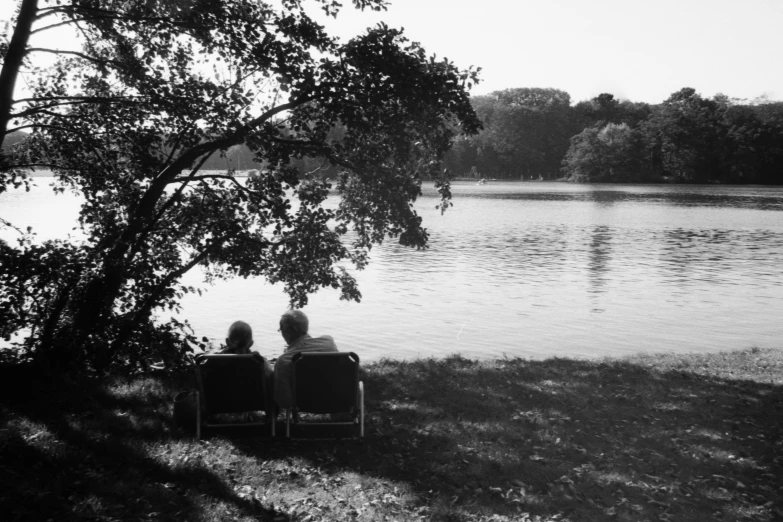 there are two people sitting by the water