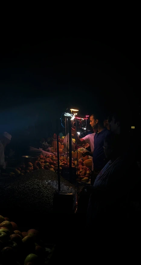 people are buying oranges from stands in a dark room