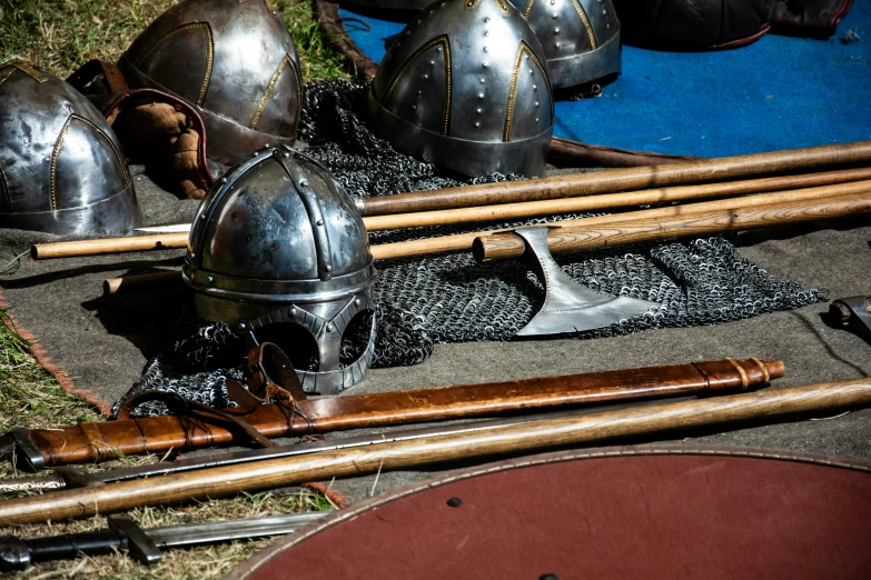several medieval helmets and weapons lay on the ground