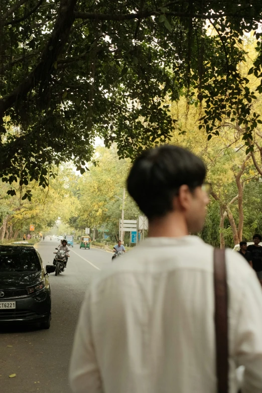 man with shoulder bag on street near parked cars