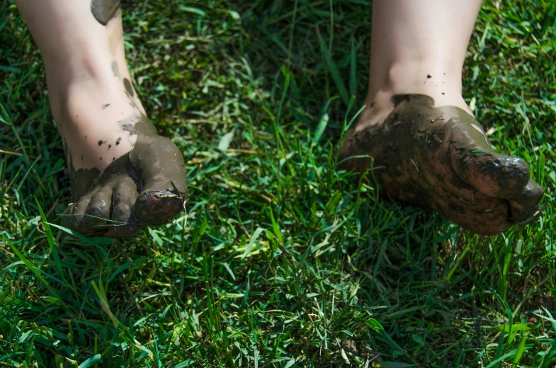 two legs in mud and grass with their toes near them