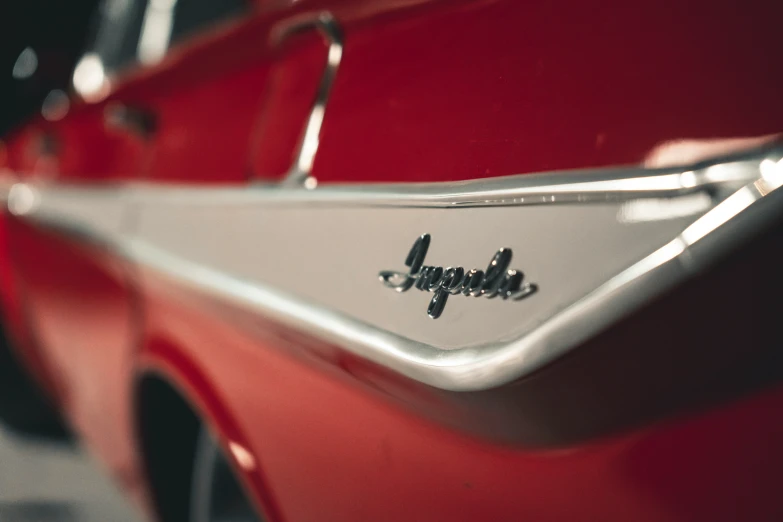 the rear end of an old red car with silver fender