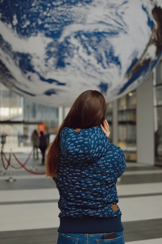 woman in blue jacket taking pictures of the earth globe