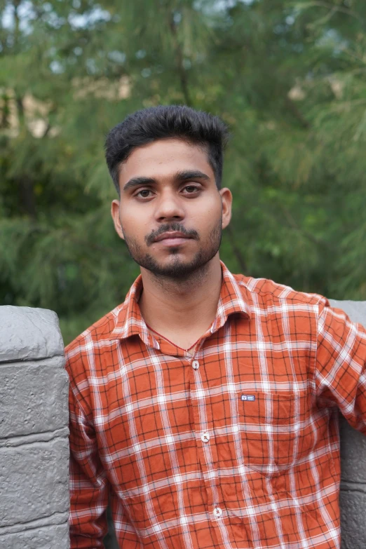 a young man is posing in front of a brick wall