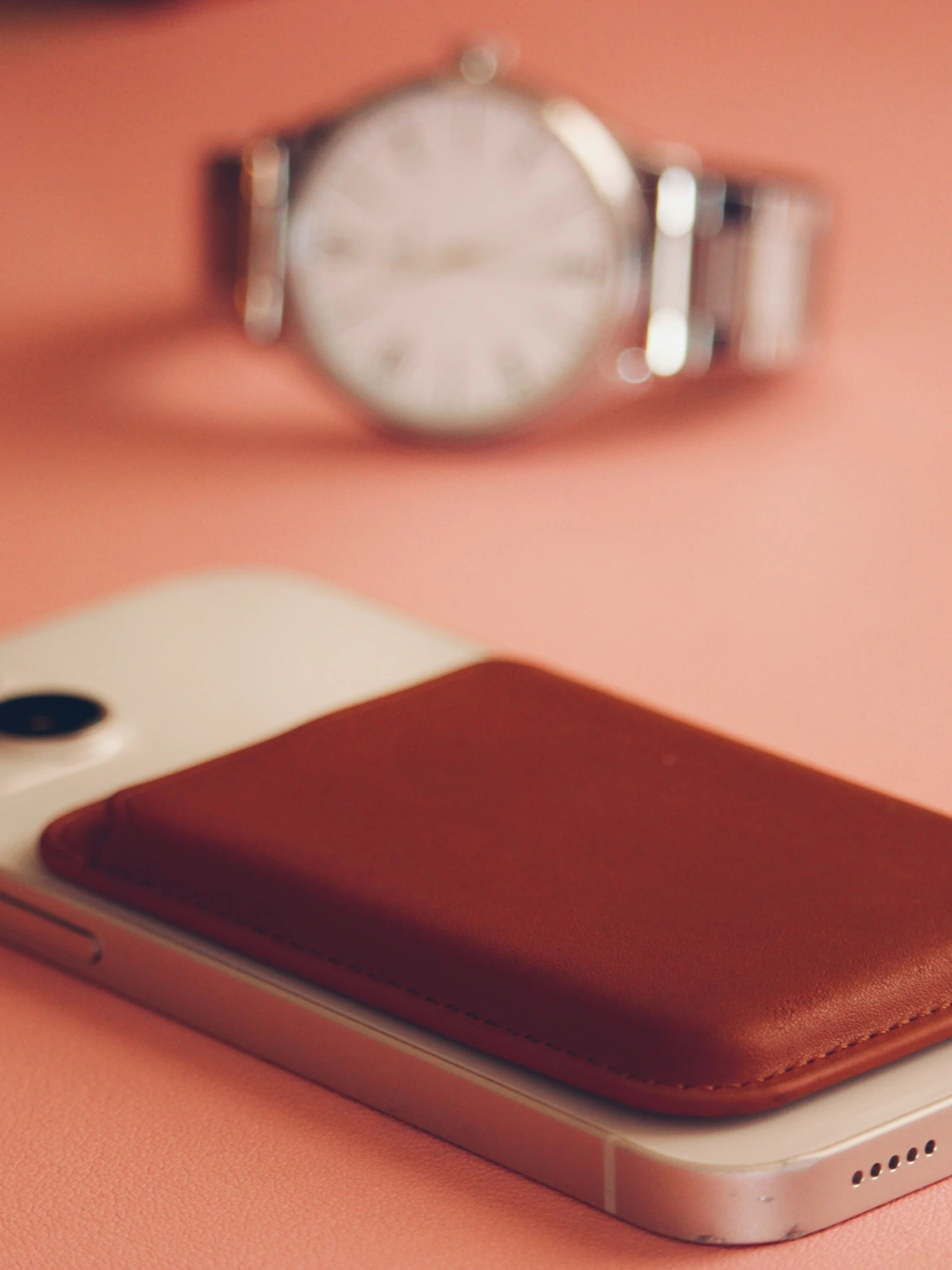 close up of a phone with a wallet and watch in the background