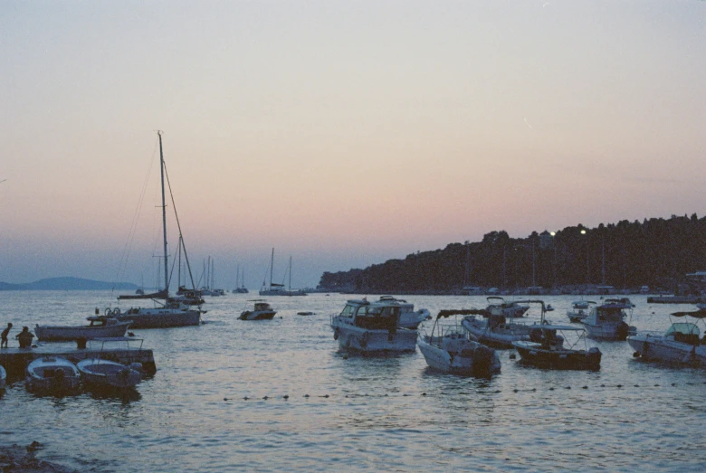 a sunset view of several boats in the harbor