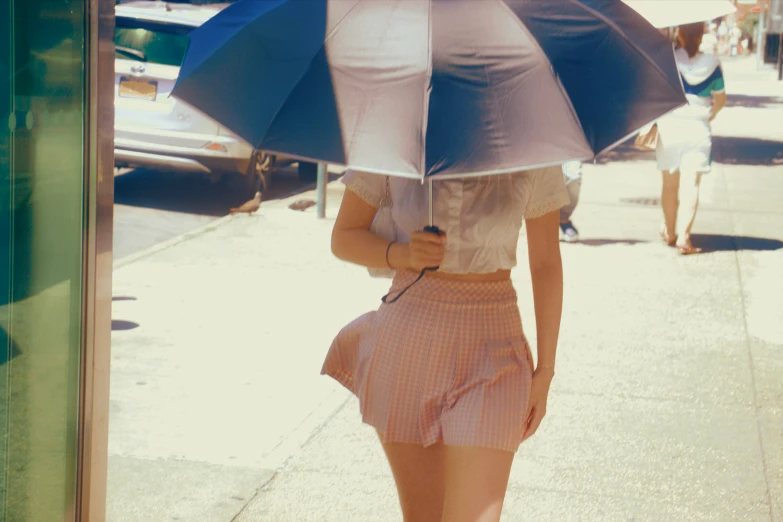 a young lady wearing short skirt and heels holds an umbrella