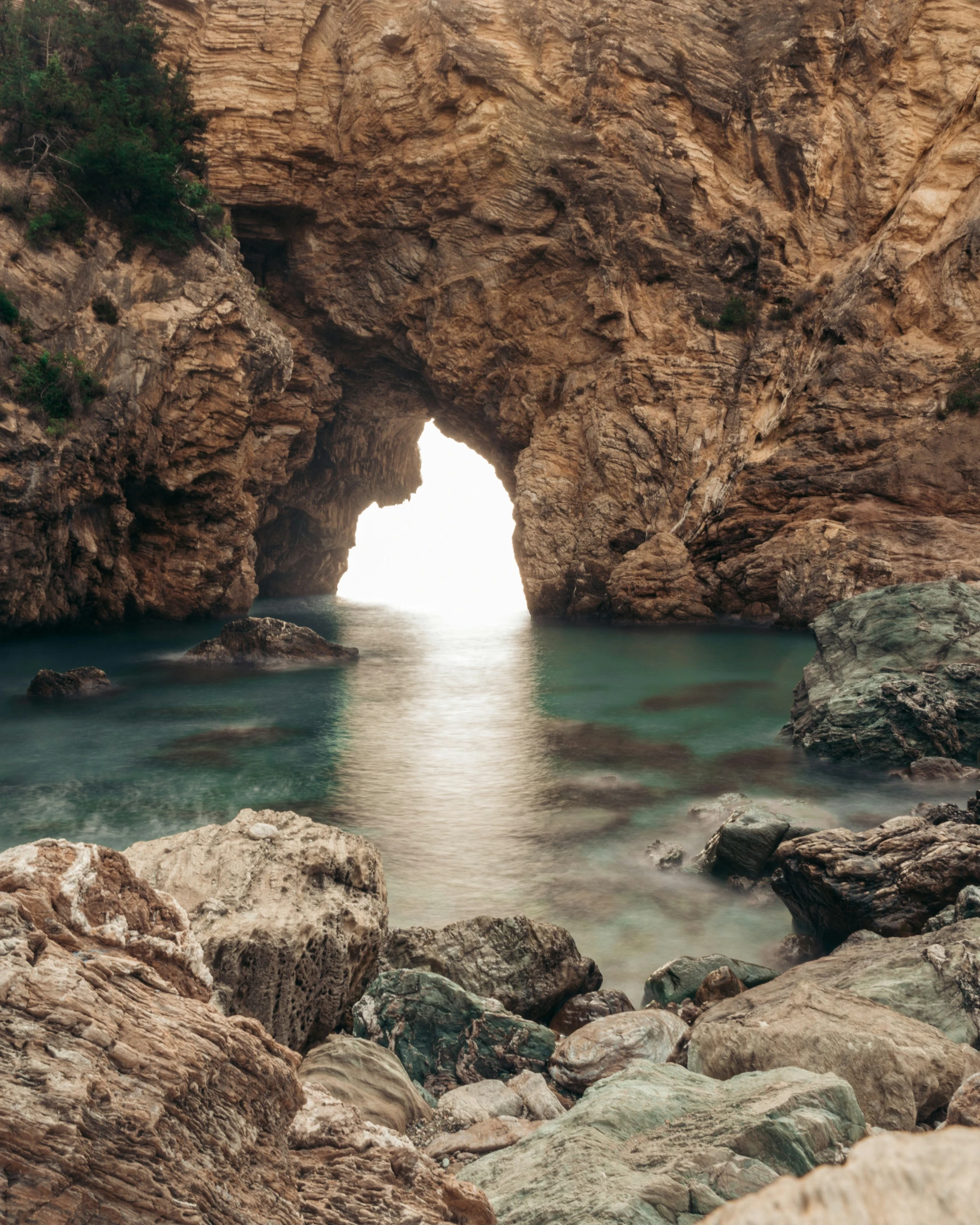 an arch in a cliff by the water