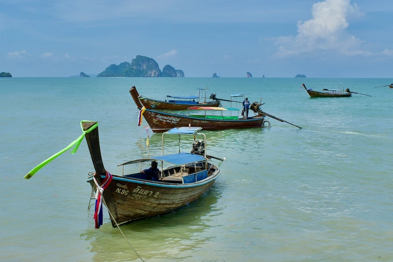 several boats are anchored and in the water at the beach