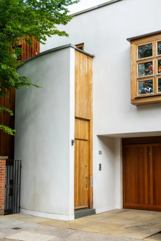 the corner of an open brick house has two wooden doors and a circular window