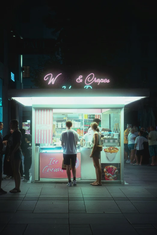 people stand outside a food stand at night