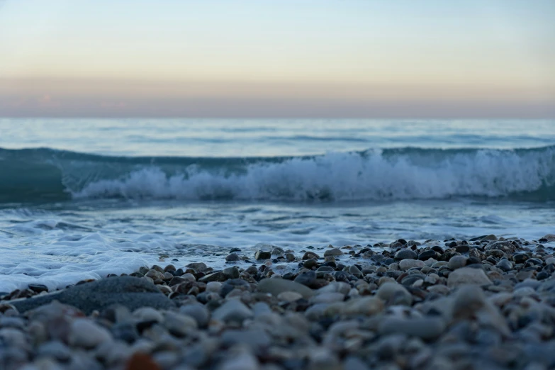 a rocky beach at sunset with a crashing wave