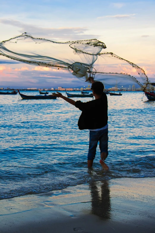 person standing on the beach, holding fishing nets