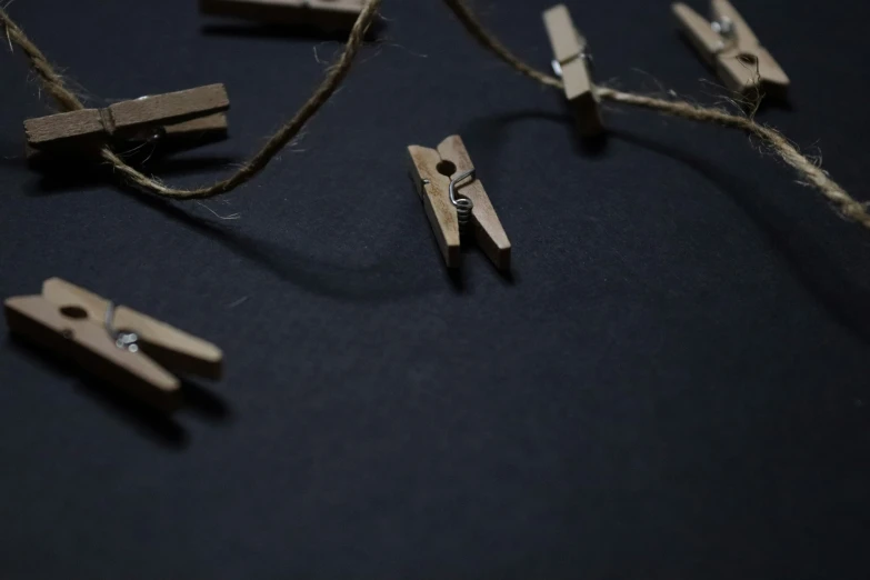 wooden clips attached to string on black surface