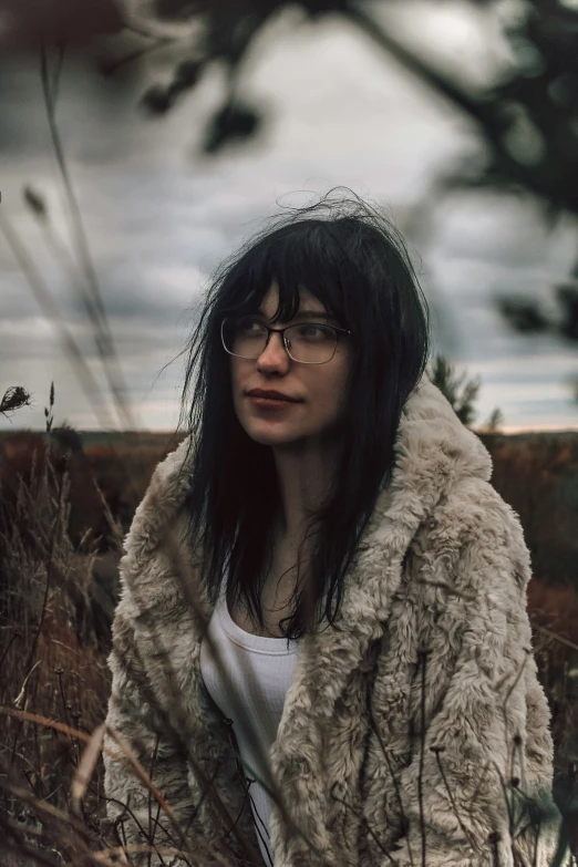 a woman standing in the grass with her arms folded