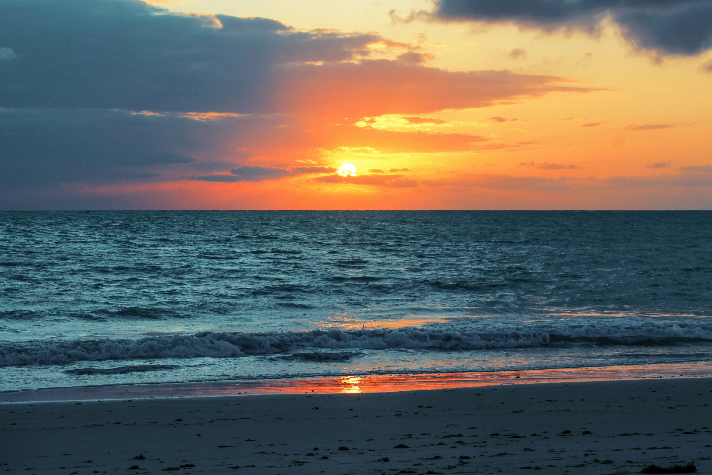 a sunset over a beach with waves and surf