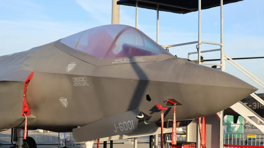 a large stealth aircraft sits on display for people to view