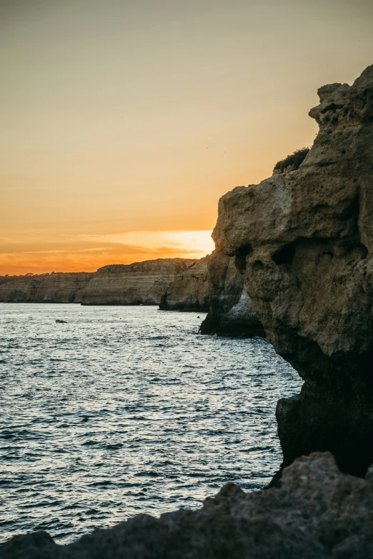 a large body of water sitting next to rocks and a hillside