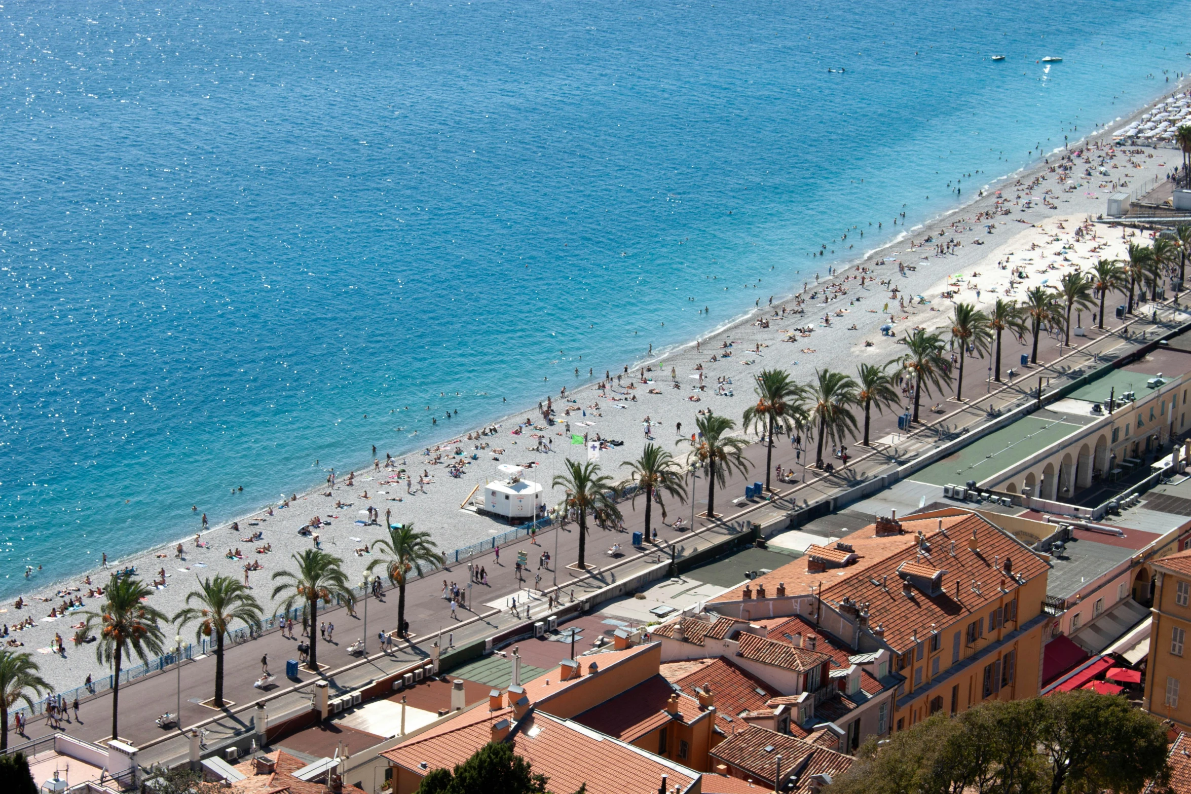 a beach with several people swimming, walking and riding water bikes