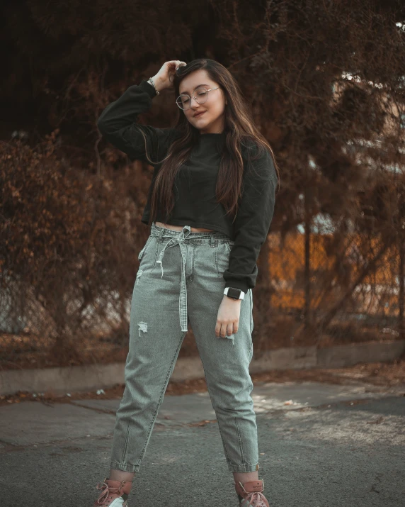 woman wearing glasses, black top and green pants